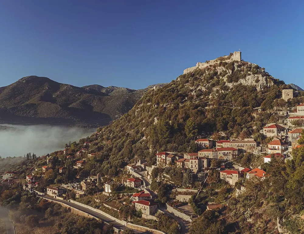 Πανοραμική άποψη της Καρύταινας με το μεσαιωνικό κάστρο της πάνω στον λόφο και τα πέτρινα σπίτια του χωριού.